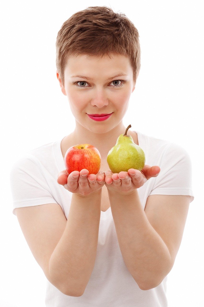 Mujer pelo corto con camiseta blanca manga corta con una manzana y una pera en las manos